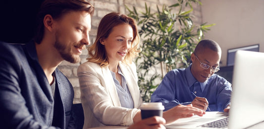 Three leaders working together around a computer